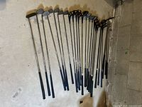 Photo showing a full set of 18 golf clubs laid out, including irons and woods with blue grips, some wear visible on shafts and heads.
