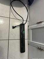 Full view of the Ember Strip 8AV+ power bar on the floor showing the entire length with attached power cable.