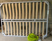 Full view of the white metal queen bed platform frame with evenly spaced wooden slats and attached middle rail.