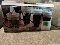 Box front showing packaging and product image of six reactive glaze stoneware mugs with dark handles and frothy beverages on the box.