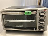 Front view of Black & Decker toaster oven showing glass door, metal handle, and control panel on the right side.