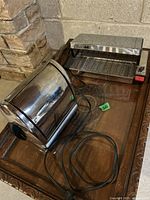 Photo showing both the cylindrical toaster and the rectangular roaster on a wooden surface.