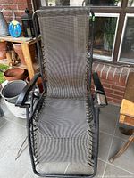 Front view of one zero gravity lounge chair showing grey mesh fabric, metal frame, and black armrests.