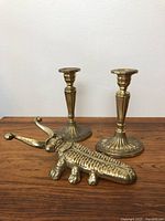 Photo showing two brass candlesticks and the brass beetle boot jack.