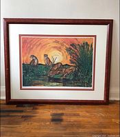 Full front view of framed print showing four cheetahs by waterhole at sunset in wood frame.