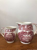 Both large and small Mason's of England Vista red ironstone pitchers shown side by side on wood surface against white background