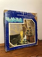 Photo of original blue and white Glas-Tile box showing vintage mirrored wall tiles in a living room setting.