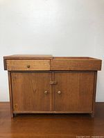 Front view of small wooden cabinet showing drawer and double doors