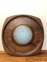 Front-facing view of the vintage teak serving tray showing the square shape and ceramic tile center with sunburst pattern.