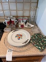Porcelain plates with Santa and holly design, ceramic mugs with Christmas tree and poinsettia prints, glass trays, apron, clear decorative items