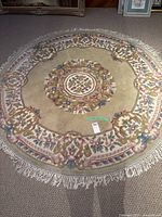 Full view of the circular area rug showing floral design and fringed edges.