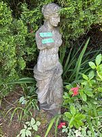 Full view of statue outdoors against shrubs