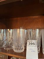 Shelf with six cut-glass highball glasses, clear with diamond lattice pattern.