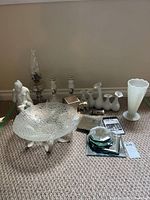 Full lot view showing glass oil lamp, textured glass bowl on feet, white vase, ceramic figurines, and small mirrors on carpeted floor.