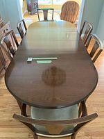 Full view of wood oval dining table with 6 chairs set around it.