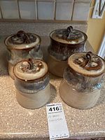Set of four pottery canisters placed on counter showing size and design