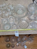 Multiple clear glass serve ware items arranged on a countertop including divided plate, bowls, small dishes, and a covered dish.