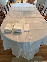 Full view of white tablecloth draped over a table with stacks of matching white cloth napkins on top