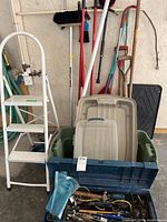Full view of ladder, garden tools, storage bins, and toolbox in garage setting