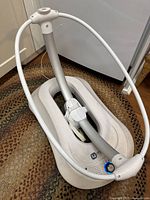 Front view of 4moms MamaRoo baby swing base with attached toy bar frame, showing power button and logo.