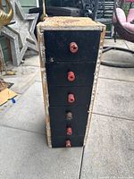 Front view of wooden organizer showing five black drawers with red knobs