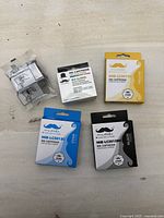 All four ink cartridges arranged on a surface: black, cyan, yellow, and color cartridges, all in original packaging with Moustache branding.