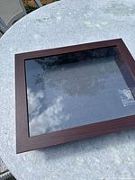 Shadow box frame closed, showing dark brown wooden frame with glass front.