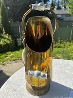 Front view of the brass fireplace tool holder showing the open front and porcelain handle.