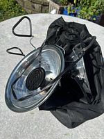 Two metal heat lamps with coiled heating elements inside a black drawstring bag, shown on a round outdoor table.