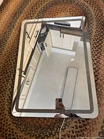 Top-down view of the rectangular LED lighted mirror on a textured surface showing color and condition.