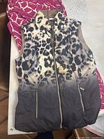 Sleeveless animal print vest with zippered pockets laid on a table