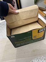 Photo showing a box of kraft paper filing folders with one folder held open.