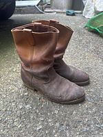 Side view of two brown leather boots showing wear and tear on toe and sides