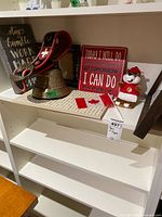 Overview of shelf with cow bell, signs, plush toy, flag items