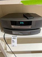 Wave Music System III stacked on multi-CD changer with remote on top, clock display illuminated