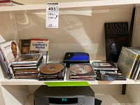 Shelf with stacks of CDs, DVDs, CD wallet and Frank Sinatra case