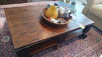Full view of coffee table showing wood top, metal legs, lower shelf and casters
