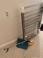 Overall shot of drying rack, iron, grabber tool leaning against wall