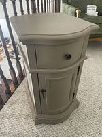 Front view of painted wood side table showing drawer, cabinet door, and hardware