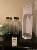 Full view of soda maker and four bottles on shelf