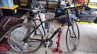 Full view of black Specialized Sirrus bicycle on stand with red floor pump