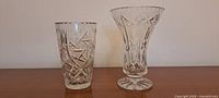Photo showing two crystal vases side-by-side on a wooden surface, highlighting the cut patterns.