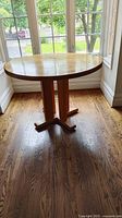 Front view of round wooden table by window.