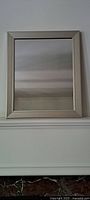 Front view of silver framed rectangular mirror showing the smooth silver wooden frame and reflective glass surface.