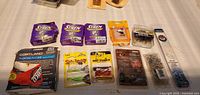 Photo showing 11 new fishing tackle items on white surface, including 3 Stren lures in purple-yellow packaging, Cortland floating fly line, and 7 other lures and accessory packs.