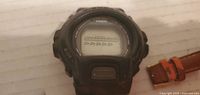 Black Casio digital wristwatch with plastic strap on a light surface.