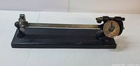 Front and top view of antique lever balance scale with circular dial and black wooden base