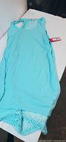 Front view of aqua sleeveless blouse showing solid fabric and tag attached.
