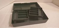 Open view of green plastic storage box showing removable inner trays and compartments.