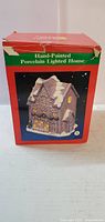 Front view of the original box for the hand-painted porcelain lighted house, showing the product image and labeling.